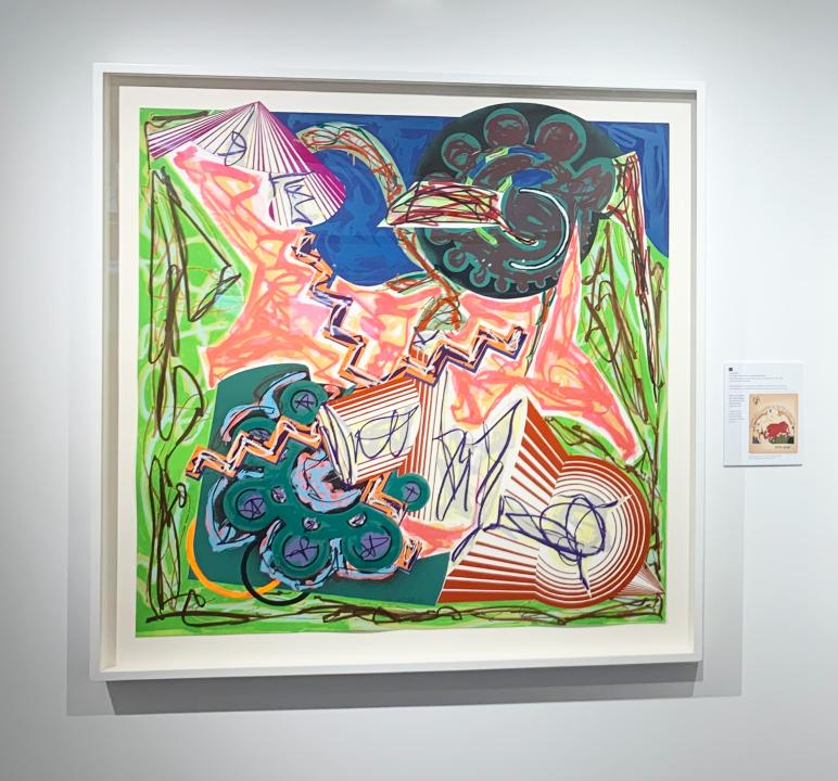 An illustration framed on wall with abstract shapes and bright greens, blues, and pinks